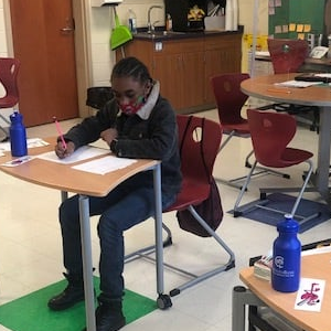 Items given to local classroom with a local student working at desk.