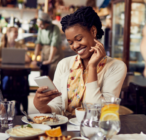 A young woman sitting in a cafe looking at a smartphone
