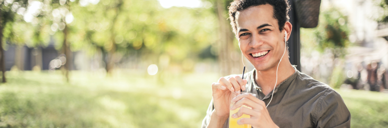 Smiling Man Drinking Juice and Listening to Music