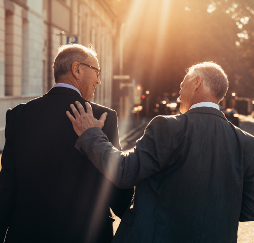 Two older men in business suits walking down a city street