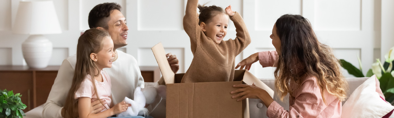 Family of four unpacking cardboard boxes