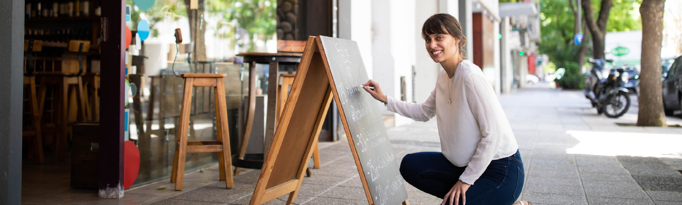 A young woman kneeling in front of a chalkboard