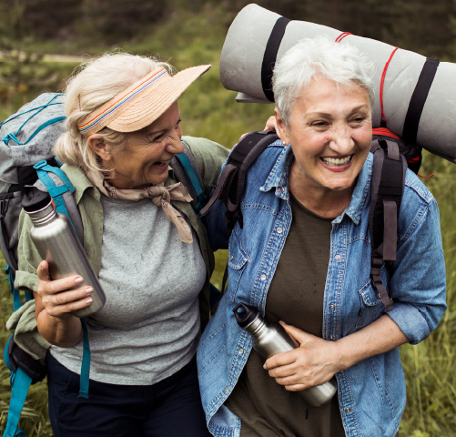 Two older women walking outside in hiking gear