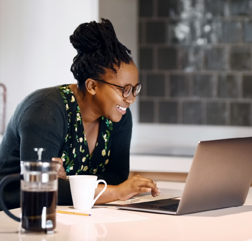 Woman standing in a kitchen looking down at a laptop