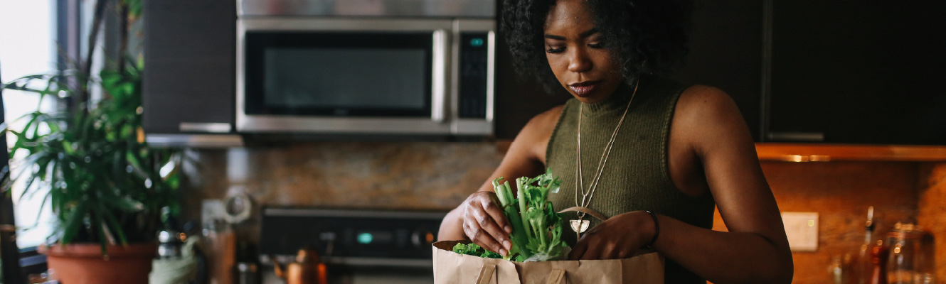 A young woman unpacking groceries in a kitchen